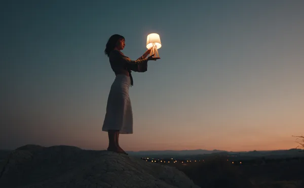 夕暮れとランプを持つ女性